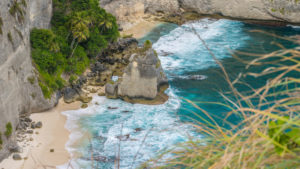 Rock in the ocean with beautiful palms behind at Atuh beach on Nusa Penida island, Indonesia. Rock in the ocean with beautiful palms behind at Atuh beach on Nusa Penida island, Indonesia.